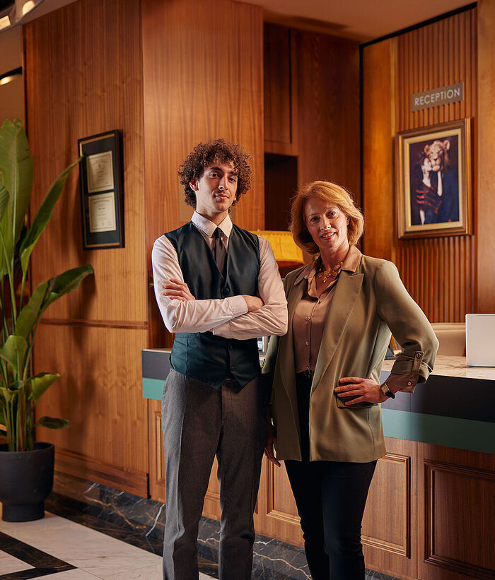 Hospitality IT Solutions A woman and a man are standing at a hotel reception; a modern laptop is on the reception counter.